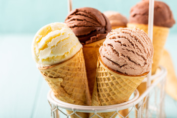 Homemade coffee, vanilla and chocolate ice cream in waffle cones on turquoise background. Healthy summer food concept with copy space.