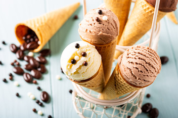 Homemade coffee, vanilla and chocolate ice cream in waffle cones on turquoise background. Healthy...