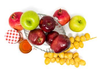 Rosh Hashanah (Jewish New Year) Traditional Symbols, Honey in a glass jar, Pomegranates, Dates, Red And Green Apples. Isolated On A White Background