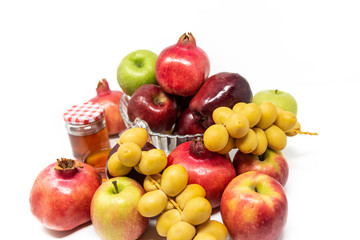 Rosh Hashanah (Jewish New Year) Traditional Symbols, Honey in a glass jar, Pomegranates, Dates, Red And Green Apples. Isolated On A White Background