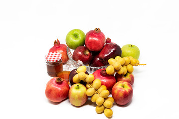 Rosh Hashanah (Jewish New Year) Traditional Symbols, Honey in a glass jar, Pomegranates, Dates, Red And Green Apples. Isolated On A White Background