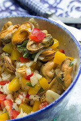 Muschelsalat mit Paprika, Tomaten, Kräutern auf einem Teller angerichtet