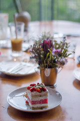A Piece of Watermelon Cake decorated by some chop of strawberries on a white plate.