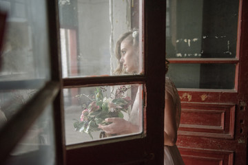 Fototapeta na wymiar Young woman posing in a pink tender light long dress indoors