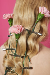 Close up rosy carnation in blonde hair of lady