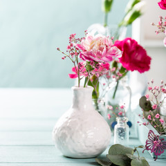Bouquet of pink carnation in glass vase on light turquoise wooden background. Mothers day, birthday greeting card. Copy space.