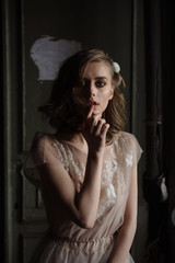 Fototapeta premium Young woman posing in a pink tender light long dress indoors