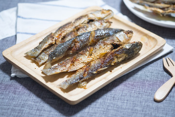 Fried mullet fish served on wood tray