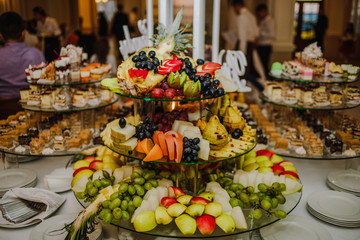 Exotic, organic fruits, light snacks in a plate on a buffet table. Assorted mini delicacies and...