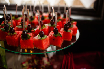 Exotic, organic fruits, light snacks in a plate on a buffet table. Assorted mini delicacies and snacks. Decorated delicious table for a party goodies