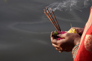  Hindu woman pray sun God, with food offerings, at dusk,in the bank of lake, during annual ritual...
