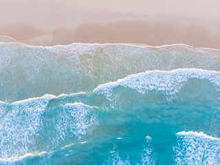 Ocean beach aerial top down view with blue water, waves with foam and spray and fine sand, beautiful summer vacation holidays destination