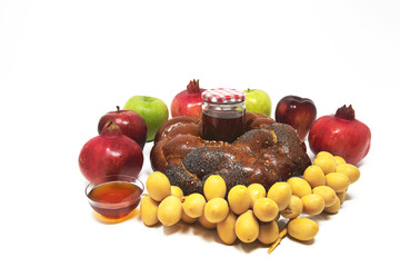 Rosh Hashanah (Jewish New Year) Traditional Symbols, Honey in a glass jar, Pomegranates, Dates, apples, Challah Bread. Isolated On A White Background
