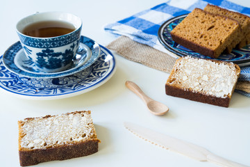  traditional Dutch spiced caked called ontbijtkoek or peperkoek, with cup of tea. Against white background