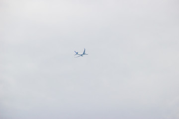 Distant airplane flying in the cloudy sky