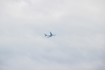 Distant airplane flying in the cloudy sky