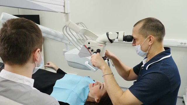 Doctor using microscope. Dentist treating patient in modern dental clinic. Orthodontist works with an assistant. The operation is carried out using special Dental Intraoral Check Digital Micro Camera