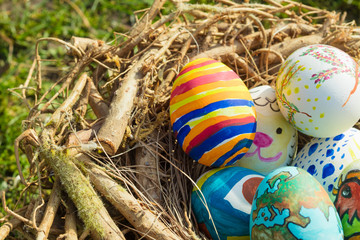 Detail of painted Easter eggs with different forms, cartoons and bright colors placed in a bird nest outdoors on a sunny day