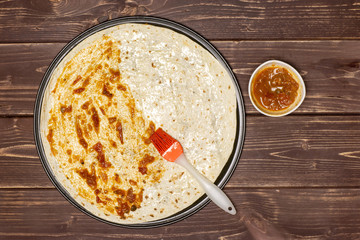 Put passata with a brush. recipe step by step pizza capricciosa flatlay on brown wood