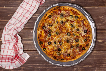 Ready to eat. recipe step by step pizza capricciosa with a tea towel on grey ceramic plate flatlay on brown wood