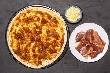 Put jamon and cheese on a pizza. recipe step by step pizza capricciosa flatlay on grey stone