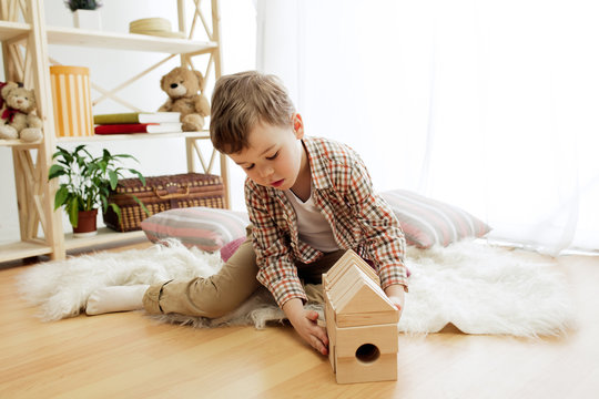 Little child sitting on the floor. Pretty boy palying with wooden cubes at home. Conceptual image with copy or negative space and mock-up for your text