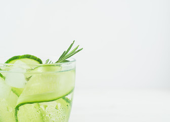 Fresh cucumber drink sprig of rosemary in a glass goblet on white background. Summer refreshing detox. Selective focus.