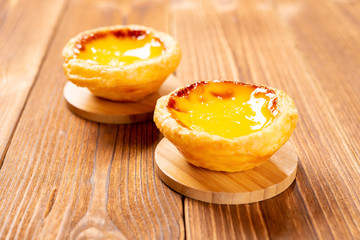 two pieces fresh portuguese egg tarts on a wood table