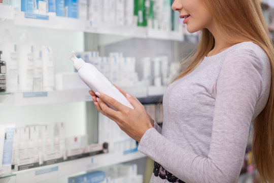 Cropped Shot Of A Female Customer Examining Label On A Product Bottle, Shopping At The Drugstore. Woman Reading Medication Label, Buying Prescription Medicine At Pharmacy, Copy Space. Health Care Conc