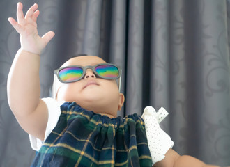 Asian baby girl  wear  sunglasses and putting her hand up in the air