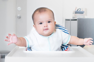 Baby waiting for mother feeding on high chair, baby eating food