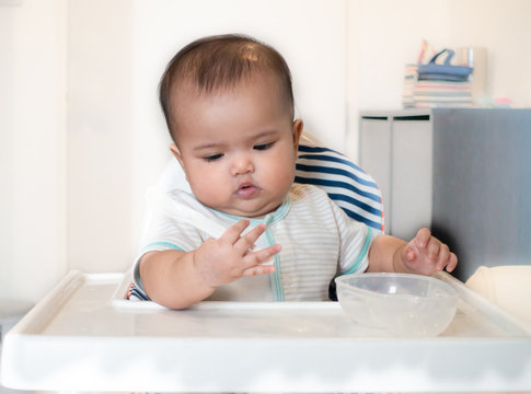 Baby playing with spoon and feeding bowl
