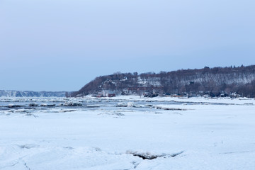Blue hour morning late winter view of ice breaking on the banks of the St. Lawrence river and houses on Cap-Rouge in the outskirts of Quebec City, Quebec, Canada
