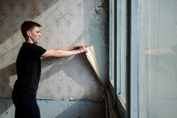 man removes old wallpaper from the wall