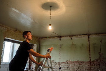 young man changes light bulb on the ceiling