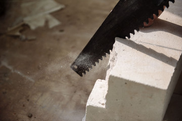 young man sawing a foam block with a saw