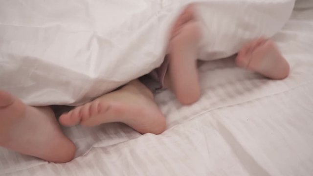 Legs of two little girls sticking out from a blanket