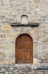 Fototapeta na wymiar The background old beige stony wall with door