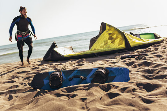 Man sufrers in wetsuits with kite equipment for surfing.