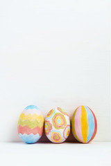 Three colorful Easter eggs decorated with geometric patterns on white background