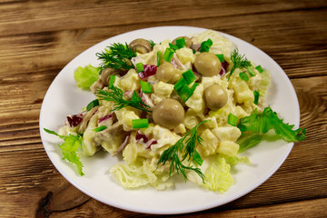 Potato salad with marinated mushrooms, eggs, red onion and mayonnaise on wooden table