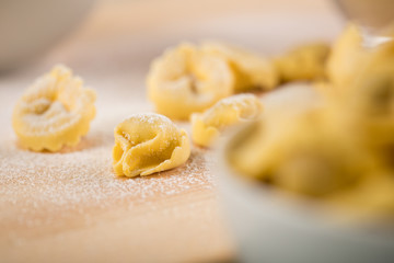 Frische, rohe Cappelletti Tortellini Pasta mit Mehl und Grieß in Porzellan Schale auf Holz Brett...