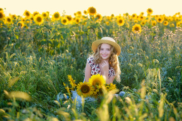 Beautiful young girl enjoying nature on the field of sunflowers at sunset