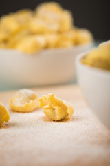 Frische, rohe Cappelletti Tortellini Pasta mit Mehl und Grieß in Porzellan Schale auf Holz Brett und Pastell Grün Hintergrund