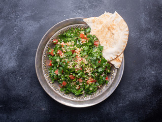 Tabbouleh salad, traditional middle eastern or arab dish. Usually prepared with parsley, mint, bulgur, tomato. Black background