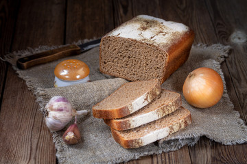 Form rye-wheat bread, sliced pieces, onions and garlic on a natural matting napkin.
