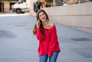 Fototapeta premium Attractive young student woman talking and chatting on her smart phone outside in an European city
