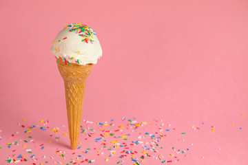 summer creative concept with ice cream cone and strewed sprinkles on pink background, festive...