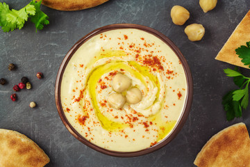 Chickpea hummus plate with pita bread, herbs, spices, olive oil. Healthy vegan dip. Top view, flat lay.