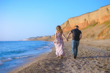 Happy couple runs in wave splashes at romantic sea sunset